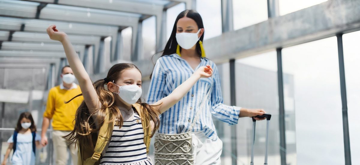 Family with two children going on holiday, wearing face masks at the airport.